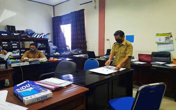 Kasi Penataan Keuangan dan Aset pada DPMD Kabupaten Gumas Chandra Novan (kanan) beraktivitas di ruang kerjanya
