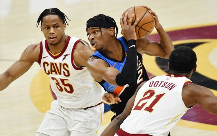 Guard Oklahoma City Thunder Shai Gilgeous-Alexander (2) melaju ke ring di antara guard Cleveland Cavaliers Isaac Okoro (35) dan guard Damyean Dotson (21) pada kuarter ketiga di Rocket Mortgage FieldHouse, 21 Februari 2021. ANTARA/Reuters/Ken Blaze-USA TODAY Sports
