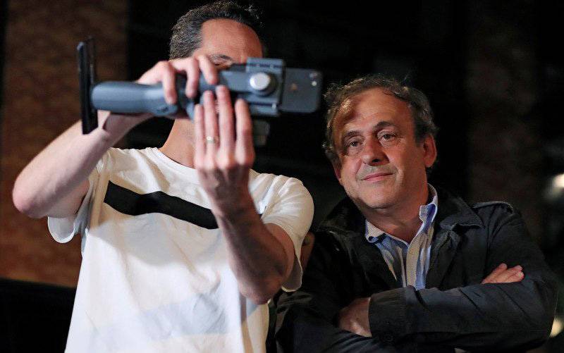 Seorang wartawan berswafoto dengan mantan kepala asosiasi sepakbola Eropa EUFA Michel Platini saat Platini meninggalkan kantor polisi yudisial dimana ia ditahan untuk diinterogasi mengenai penghargaan turnamen sepakbola Piala Dunia 2022 di Nanterre, Prancis, Rabu (19/6/2019). (foto : REUTERS/GONZALO FUENTES)