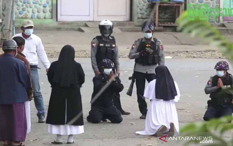 Seorang biarawati Suster Ann Rose Nu Tawng (kedua kanan) berlutut di depan aparat kepolisian untuk memohon mereka agar menahan diri dari kekerasan terhadap anak-anak dan penduduk, di tengah unjuk rasa anti kudeta militer di Myitkyina, Myanmar, Senin (8/3/2021), seperti terlihat di dalam foto yang diambil dari potongan video
