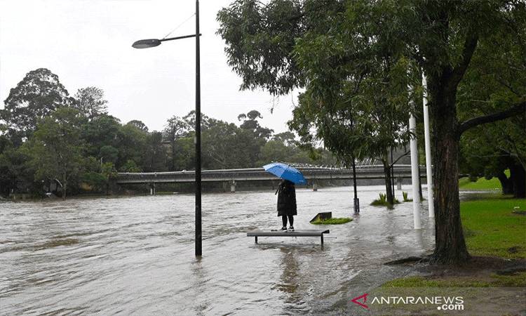 Warga berdiri di bangku taman yang terendam banjir akibat luapan Sungai Parramatta di Sydney, Australia, Sabtu (20/3/2021). ANTARA FOTO/REUTERS/Jaimi Joy/foc