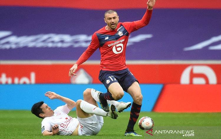 Gelandang Nimes Andres Cubas (kiri) berusaha merebut penguasaan bola dari penyerang Lille Burak Yilmaz dalam lanjutan Liga Prancis di Stadion Pierre-Mauroy, Lille, Prancis, Minggu (21/3/2021) waktu setempat. (ANTARA/AFP/Francois Lo Presti)