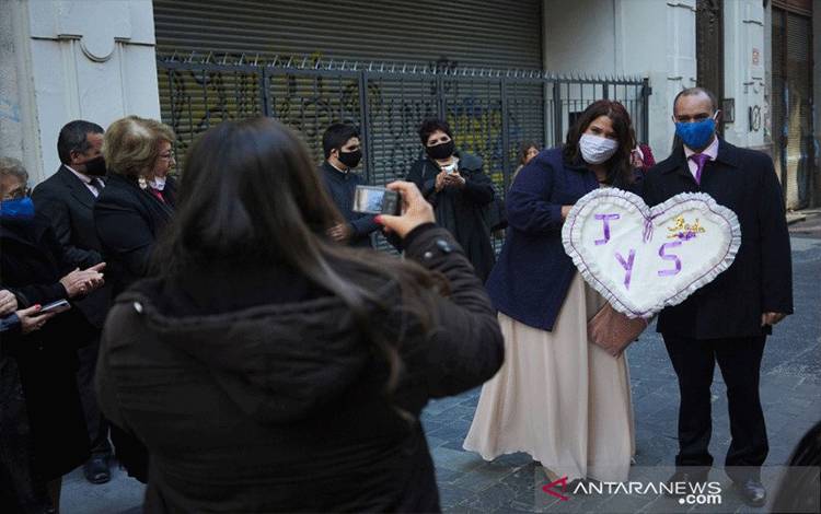 Pasangan baru menikah Sofia Antunez (ki) dan Jonathan Malacria berfoto bersama sambil memakai masker pelindung setelah menikah di kantor pendaftaran status sipil di tengah penyebaran penyakit virus korona (COVID-19) di Montevideo, Uruguay, Jumat (8/5/2020). REUTERS/Mariana Greif/hp/cfo (REUTERS/MARIANA GREIF)