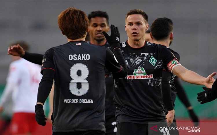 Penyerang Werder Bremen Yuya Osako (tampak punggung) melakukan selebrasi bersama Niklas Moisander seusai mencetak gol ke gawang Jahn Regensburg dalam laga perempat final Piala DFB Pokal di Jahnstadion Regensburg, Regensburg, Jerman, Rabu (7/4/2021) waktu setempat