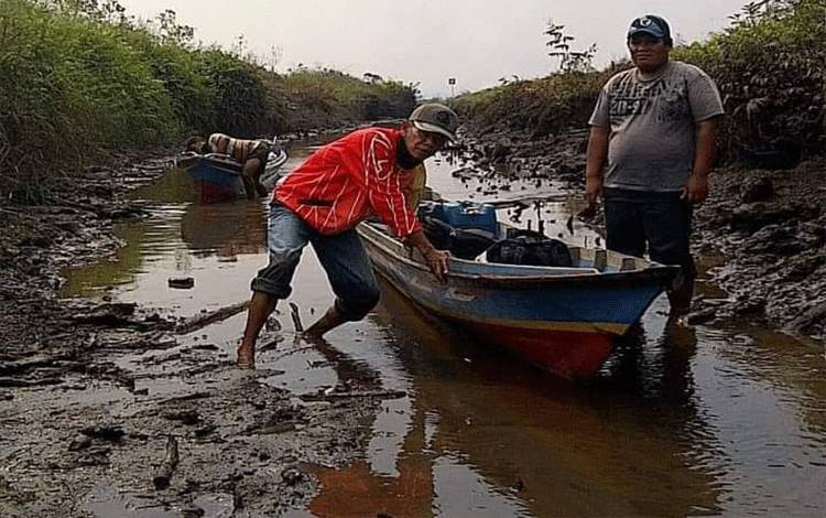 Warga berusaha mendorong kelotoknya saat mengarungi Kerukan Hantipan.?