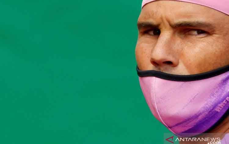 Petenis Spanyol Rafael Nadal berjalan di lapangan memakai masker pelindung sebelum pertandingan set ketiga melawan petenis Bulgaria Grigor Dmitrov pada kejuaraan tenis ATP Masters 1000 Monte Carlo Masters, di Monte-Carlo Country Club, Roquebrune-Cap-Martin, Prancis, Kamis (15/4/2021)