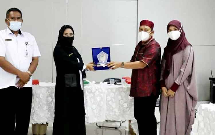 Kepala Dinas Budparpora Kabupaten Barito Utara, Annisa Cahyawati menyerahkan cinderamata kepada anggota Komisi III DPRD Kotabaru, Rustam Efendi.