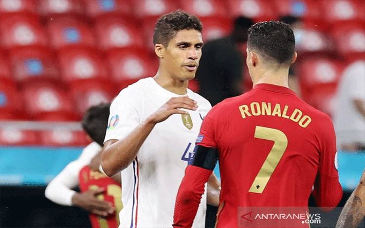Bek tim nasional Prancis Raphael Varane (kiri) bersalaman dengan kapten Portugal Cristiano Ronaldo seusai main imbang 2-2 dalam laga pemungkas Grup F Euro 2020 di Stadion Puskas Arena, Budhapest, Hongaria, Rabu (23/6/2021) waktu setempat. (ANTARA/REUTERS/POOL/Bernadett Szabo)