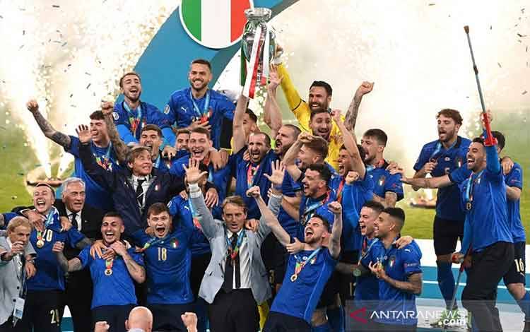 Kapten tim nasional Italia Giorgio Chiellini mengangkat trofi Henri Delauney dikelilingi rekan-rekannya dan pelatih Roberto Mancini seusai menjuarai Euro 2020 dengan mengalahkan Inggris lewat adu penalti dalam partai final di Stadion Wembley, London, Inggris, Minggu (11/7/2021) waktu setempat. (foto : ANTARA/REUTERS/POOL/Facundo Arrizabalaga)