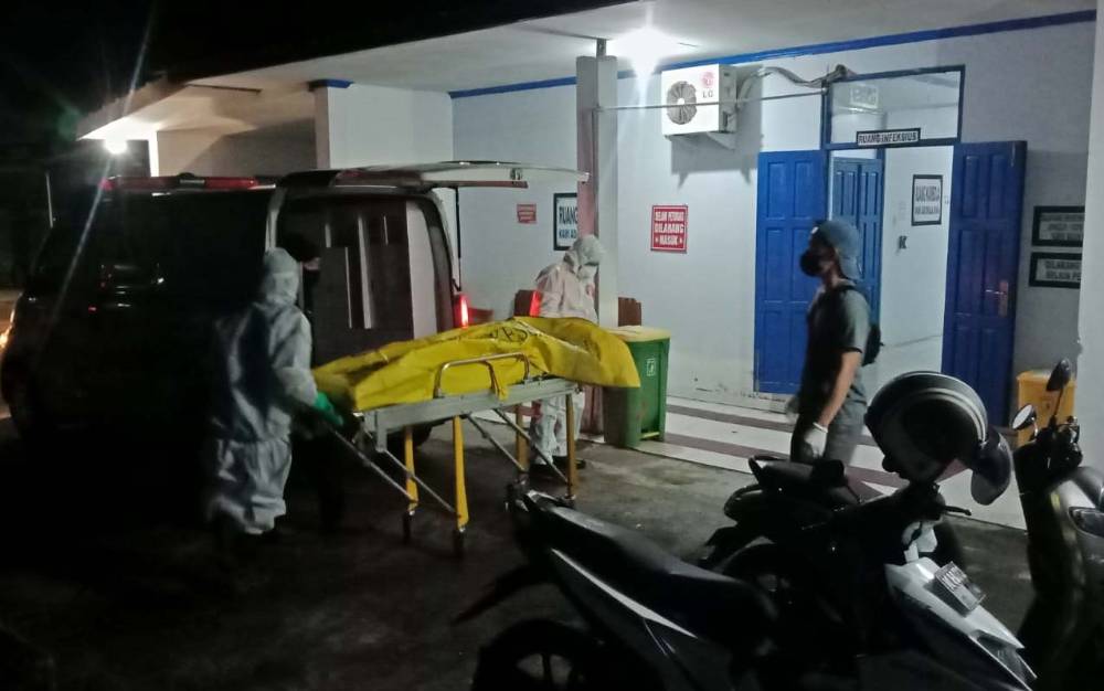Petugas mengevakuasi jenazah pria yang ditemukan tergeletak di depan SPBU Raut, Buntok, Jumat malam, 17 Juli 2021.