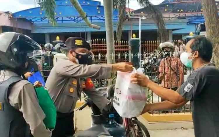 Wakil Direktur Ditsamapta Polda Kalteng saat memberikan bantuan kepada warga yang melaksanakan isolasi mandiri di rumah