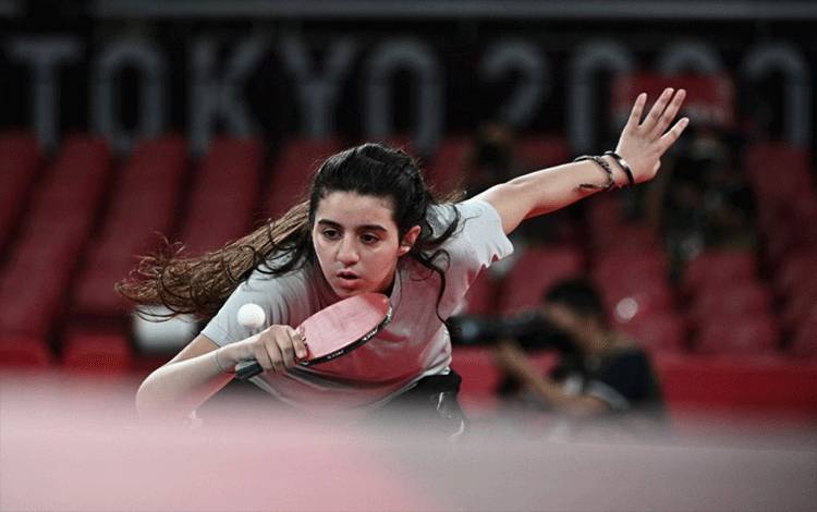 Petenis meja Suriah Hend Zaza bersiap serve saat melawan atlet Austria Liu Jia dalam babak penyisihan tunggal putri tenis mejad di Tokyo Metropolitan Gymnasium dalam Olimpiade Tokyo 2020 di Tokyo pada 24 Juli 2021. (AFP/ANNE-CHRISTINE POUJOULAT)