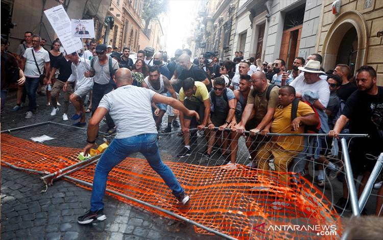 Pengunjuk rasa di Roma, Italia, Selasa (27/7/2021), memindahkan penghalang yang dipasang polisi untuk memblokir aksi demo menentang rencana Green Pass (kartu kesehatan), sertifikat digital, atau kertas yang menunjukkan jika seseorang telah menerima setidaknya dosis pertama vaksin, teruji negatif atau telah sembuh dari COVID-19. Kartu itu direncanakan untuk diwajibkan pada orang-orang yang ingin makan di dalam ruangan serta menghadiri acara budaya atau olahraga mulai pekan depan. ANTARA FOTO/REUT