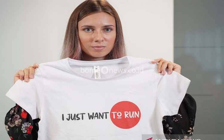 Pelari Belarus Krystsina Tsimanouskaya, yang meninggalkan Olimpiade di Tokyo dan mencari suaka di Polandia, memegang t-shirt pada konferensi pers di Warsawa, Polandia (5/8/2021)