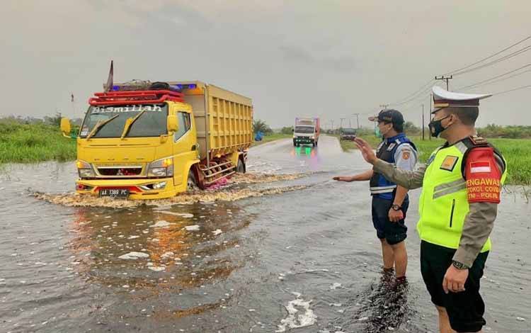 Anggota Satlantas Polres Kobar mengatur lalu lintas di jalan Lintas Pangkalan Bun - Kolam yang terendam banjir