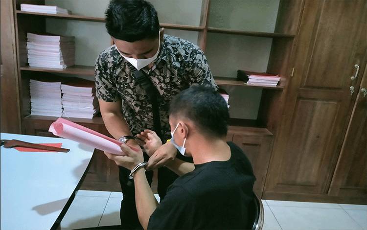 Petugas kepolisian saat melepaskan borgol dari tangan tersangka Miming.
