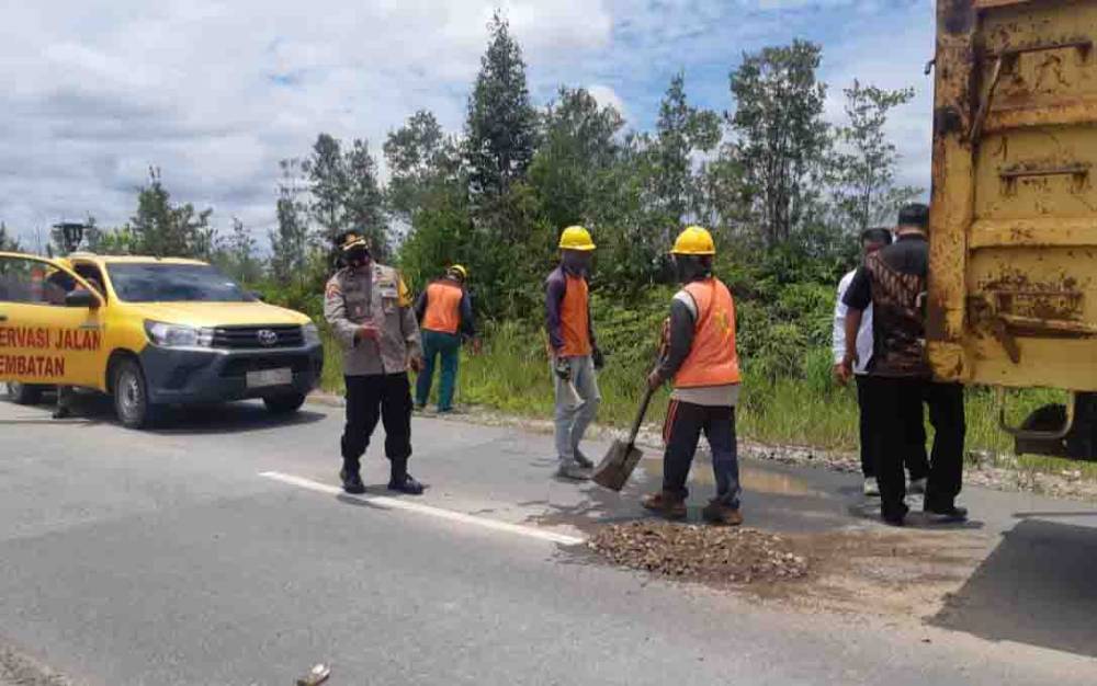 Petugas Dinas PU bersama Polres Katingan memperbaiki jalan berlubang.
