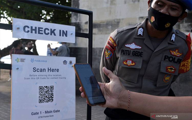 Wisatawan memindai QR Code dengan aplikasi PeduliLindungi sebelum memasuki kawasan wisata Pantai Kuta, Badung, Bali, Minggu (26/9/2021). ANTARA FOTO/Fikri Yusuf/foc. (ANTARA FOTO/FIKRI YUSUF)