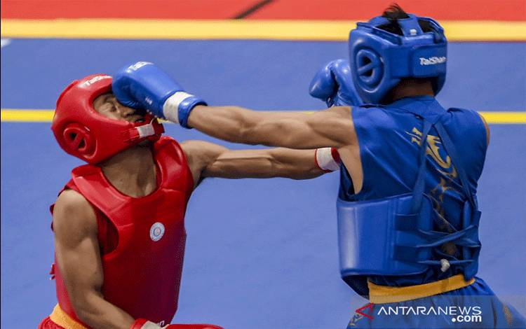 Atlet Jabar Jimy Stif Menda (kanan) memukul lawannya atlet Jateng Yusuf Widianto (kiri) pada laga semifinal wushu nomor sanda putra kelas 56 kg PON XX Papua di GOR Futsal Dispora, Kabupaten Merauke, Papua, Jumat (1/10/2021). ANTARA FOTO/Galih Pradipta/YU