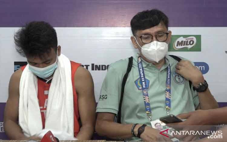 Pelatih tim bola basket putra Sulawesi Utara Roland Lengkong (kanan) dan pemainnya Greans Tangkulung memberikan keterangan kepada media usai timnya berhadapan dengan Bali pada laga Pool B PON XX Papua di Mimika Sport Complex, Mimika, Selasa (5/10/2021). Sulawesi Utara memenangkan pertandingan itu dengan skor 86-56 dan melaju ke semifinal PON Papua. (Michael Siahaan)