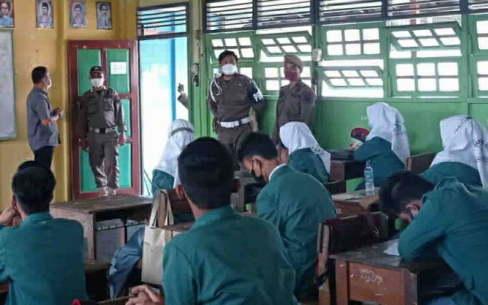 Personel Satpol PP dan Damkar Kapuas mengecek penerapan Prokes pada PTM di sekolah.