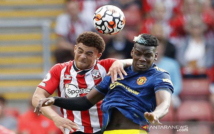 Arsip - Pemain Manchester United Paul Pogba (kanan) berebut bola dengan pemain Southampton Che Adams dalam laga lanjutan Liga Inggris di St Mary's Stadium, Southampton, Inggris, Minggu (22/8/2021). Laga tersebut berakhir imbang 1-1. ANTARA FOTO/REUTERS/Peter Nicholls/foc.