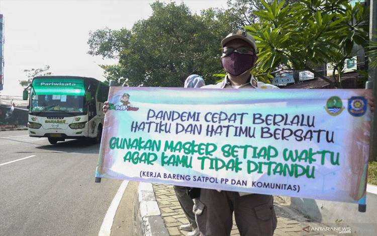 Dokumentasi. Petugas Satpol PP membentangkan spanduk imbauan untuk selalu taat prokes di Jl. Cut Mutia, Bekasi, Jawa Barat, Rabu (8/9/2021). ANTARA FOTO/Paramayuda/aww. (Antara Foto/Paramayuda)