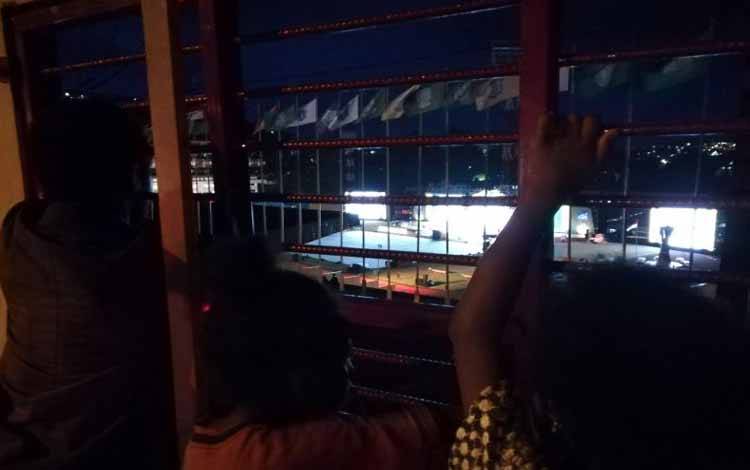 Sejumlah orang menonton pembukaan Pekan Paralimpik Nasional (Perpanas) XVI Papua melalui sela-sela tembok Stadion Mandala, Jayapura, Papua, Jumat (5/11/2021)