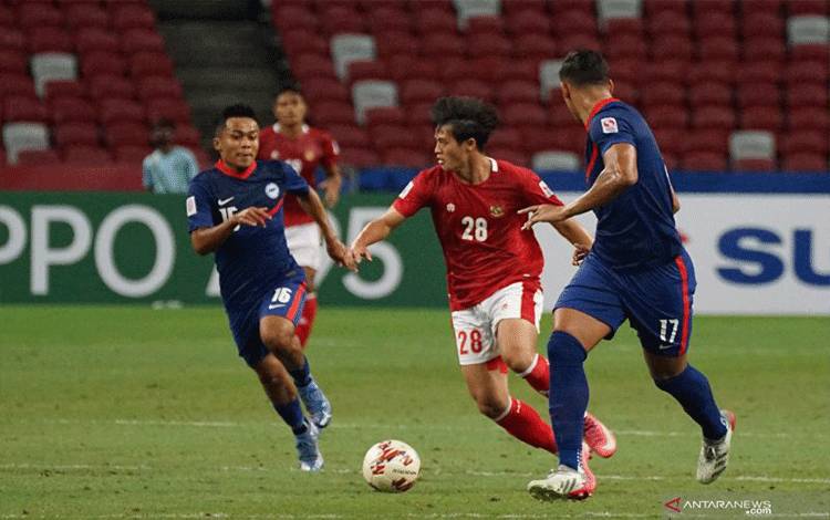 Pesepak bola Timnas Indonesia Alfreanda Dewangga (tengah) berusaha masuk ke pertahanan lawan dengan dibayangi pesepak bola Timnas Singapura Hami Syahin (kiri) dalam pertandingan Semi Final Leg 2 Piala AFF 2020 di National Stadium, Singapura, Sabtu (25/12/2021). Indonesia melaju ke babak final usai melibas Singapura 4-2 (5-3). ANTARA FOTO/Humas PSSI/Handout/app/wsj.