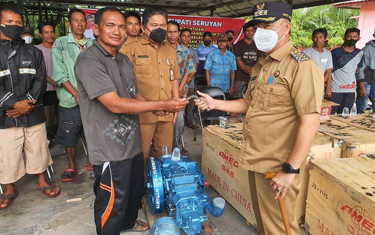 Bupati Seruyan Yulhaidir saat menyerahkan bantuan mesin kepada salah satu perwakilan kelompok nelayan penerima.