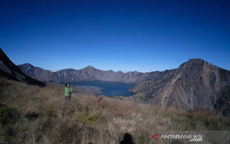 Seorang wisatawan menikmati panorama Danau Segara Anak di atas Gunung Rinjani di Pulau Lombok, NTB. ANTARA/Riza Fahriza.