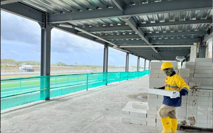 Salah seorang pekerja sedang memindahkan bata putih di lokasi tribun VIP Village yang nantinya bisa menampung 2.400 orang penonton pada perhelatan MotoGP di Pertamina Mandalika International Street Circuit di Kabupaten Lombok Tengah, Nusa Tenggara Barat (NTB), Jumat (28/1/2022). (ANTARA/Nur Imansyah).