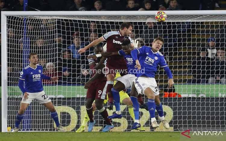 Bek West Ham Craig Dawson (melompat tengah) berhasil mencetak gol ketika berhadapan dengan Leicester City pada pekan ke-25 Liga Inggris di Stadion King Power, Leicester, Inggris, Minggu (13/2/2022)