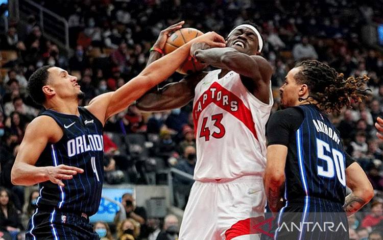 Bintang Toronto Raptors Pascal Siakam (tengah) berjibaku mempertahankan penguasaan bola di tengah kawalan dua pemain Orlando Magic Jalen Suggs (kiri) dan Cole Anthony dalam lanjutan NBA di Scotiabank Arena, Ontario, Kanada, Jumat (4/3/2022) waktu setempat. (ANTARA/REUTERS/USA TODAY SPORTS/John E. Sokolowski)