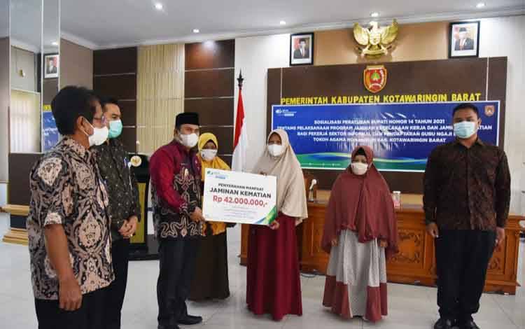Wakil Bupati Kobar, Ahmadi Riansyah menyerahkan secara simbolis manfaat jaminan kematian sebesar Rp 42.000.000 kepada peserta jaminan sosial