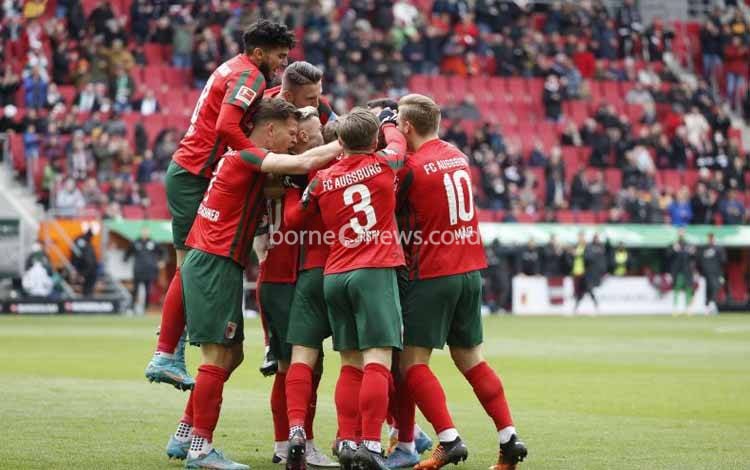 Lago diselamati rekan-rekan satumnya ketika FC Augsburg menang besar 3-0 atas VfL Wolfsburg di WWK Arena, Augsburg, Minggu 3 April 2022