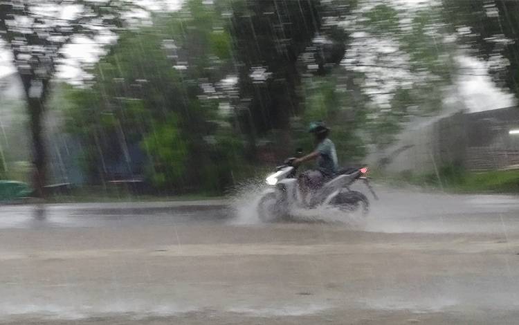 Warga menerobos deras hujan yang terjadi di Sampit, Kotawaringin Timur.