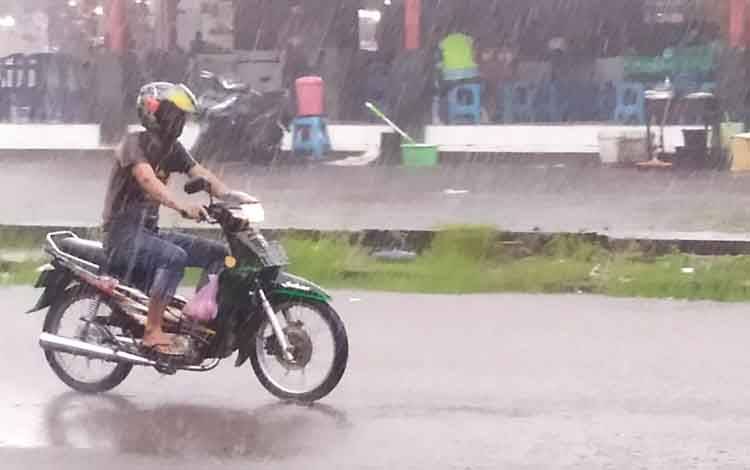 Seorang pengguna jalan menerobos derasnya hujan yang terjadi di Sampit, Kotawaringin Timur