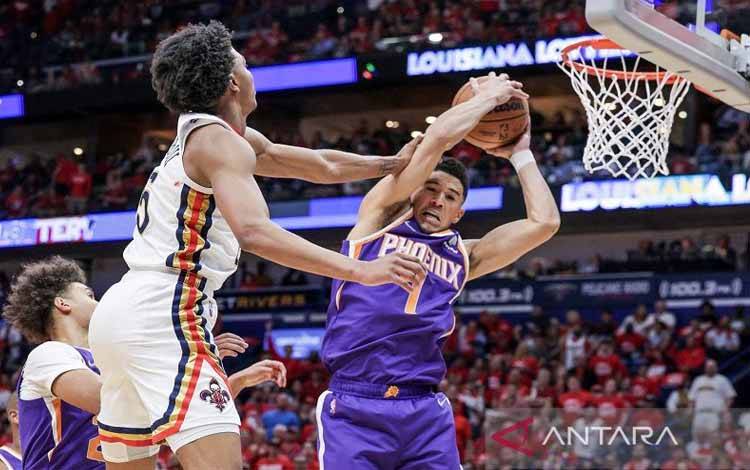 Bintang Phoenix Suns Devin Booker (kanan) dilanggar oleh pemain New Orleans Pelicans Herbert Jones dalam Gim 6 putaran pertama playoff Wilayah Barat NBA di Smoothie King Center, Louisiana, Amerika Serikat, Kamis (28/4/2022).