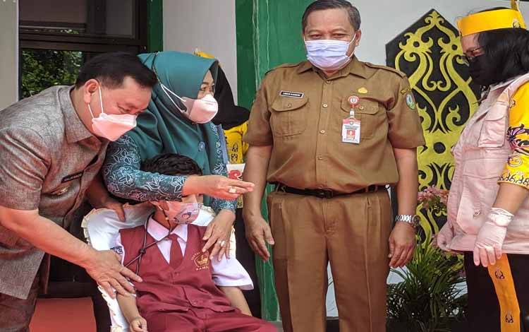Bupati Kotim Halikinnor bersama istri dan Plt Kepala Dinkes Kotim saat menemani seorang anak yang akan disuntik imunisasi