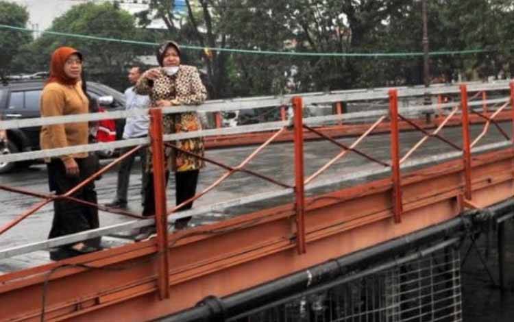 Wali Kota Surabaya Tri Rismaharini (sekarang Mensos) bersama dengan kepala Badan Perencanaan Pembangunan Kota Surabaya (Bappeko) Surabaya Eri Cahyadi (sekarang Wali Kota Surabaya) saat meninjau Jembatan Peneleh, Kota Surabaya, pada 2017