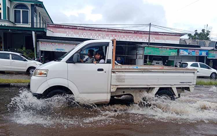 Pengendara pikap saat melintasi banjir di Jalan Tilung