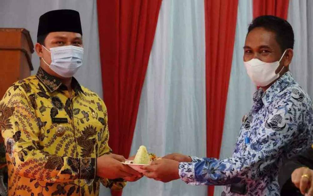 Camat Lamandau Agus Siswanto menyerahkan potongan nasi tumpeng kepada Bupati Lamandau Hendra Lesmana saat pucak peringatan Hari Jadi Kecamatan Lamandau.
