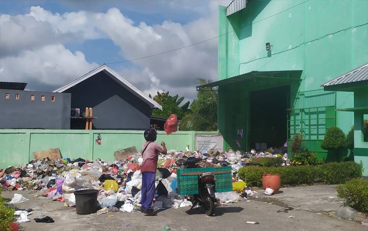 Salah seorang warga melempar bungkusan sampah di luar depo di Jalan Pelita Sampit, Kotawaringin Timur yang sampahnya meluber ke luar depo karena tak terangkut