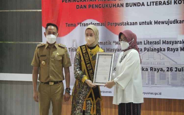 Sekretaris Utama Perpustakaan Nasional RI Ofy Sofiana menyerahkan piagam untuk Bunda Literasi Palangka Raya, Avinas Fairid Naparin. (Foto:HENDRI)