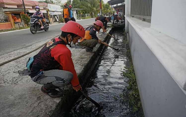 Tim TRC BPBD Kota Palangka Raya saat mengeruk lumpur yang menjadi masalah tergenangnya saluran drainase