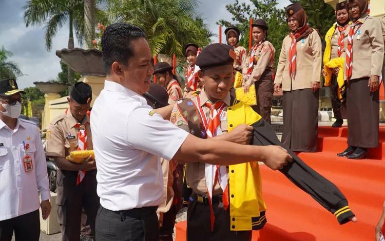 Mengenakan jaket kontingen kepada salah satu pramuka penggalang peserta Jambore Nasional.(FOTO : HENDI NURFALAH)