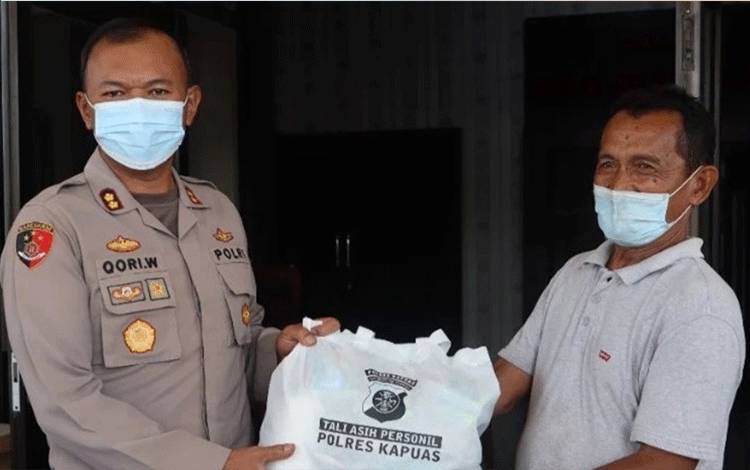 Kapolres Kapuas AKBP Qori Wicaksono saat membagikan sembako kepada warga lewat program seribu rupiah sehari. (FOTO: POLRES KAPUAS)