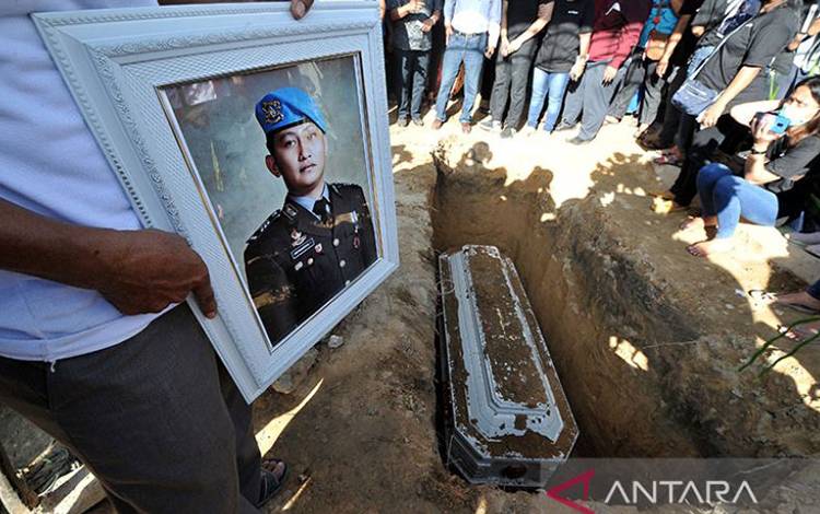 Kerabat memegang foto almarhum Brigadir Nofriansyah Yosua Hutabarat atau Brigadir J saat pemakaman kembali jenazah setelah autopsi ulang di Sungai Bahar, Muarojambi, Jambi, Rabu (27/7/2022). Autopsi ulang yang berlangsung selama enam jam itu dilakukan atas permintaan keluarga dalam mencari keadilan dan pengungkapan kasus. ANTARA FOTO/Wahdi Septiawan/nym.