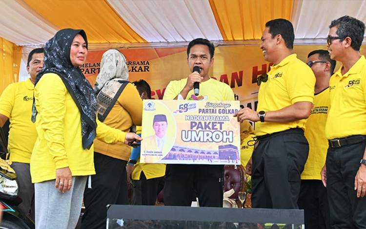 Ketua DPD Partai Golkar Kabupaten Lamandau Hendra Lesmana menyerahkan hadiah utama berupa tiket Umrah kepada Rahmat Akbar Pradana. (FOTO: HENDI NURFALAH)